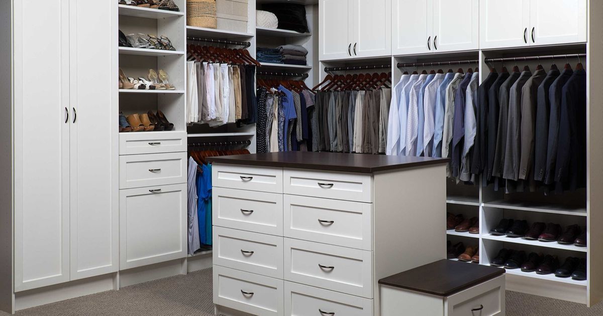 White walk-in closet with island, built-in shelves, and hanging clothes.