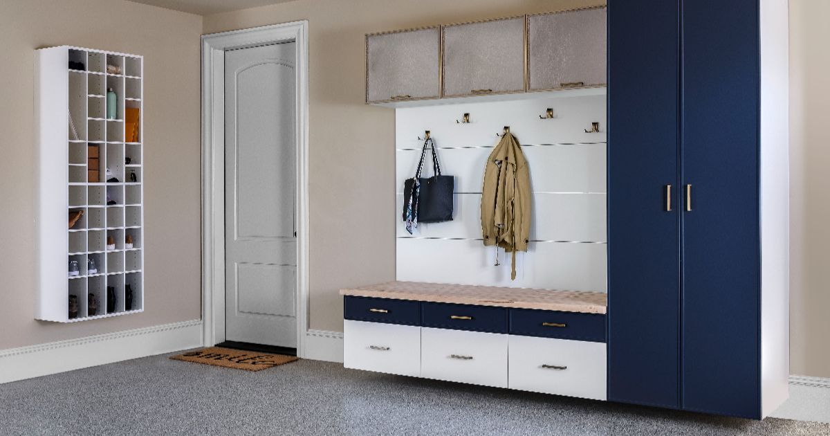 Modern entryway with white bench, coat hooks, mirror, and blue wardrobe beside a door