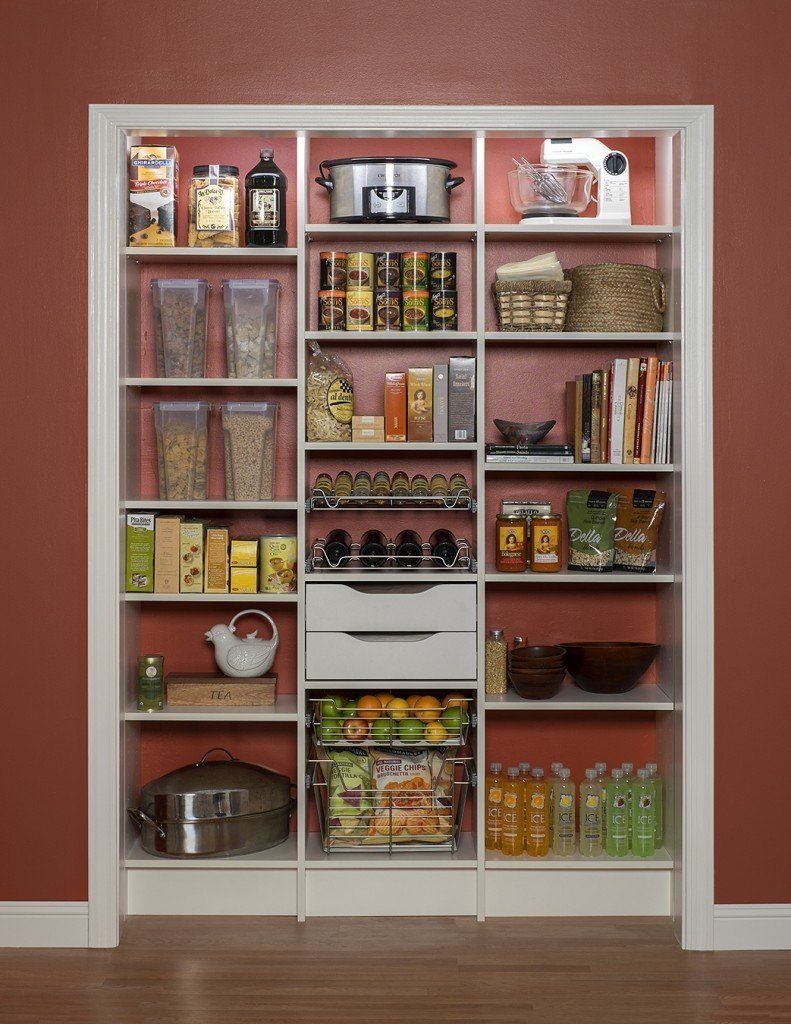 White pantry shelving stocked with jars, cans, baskets, and food containers against a red wall
