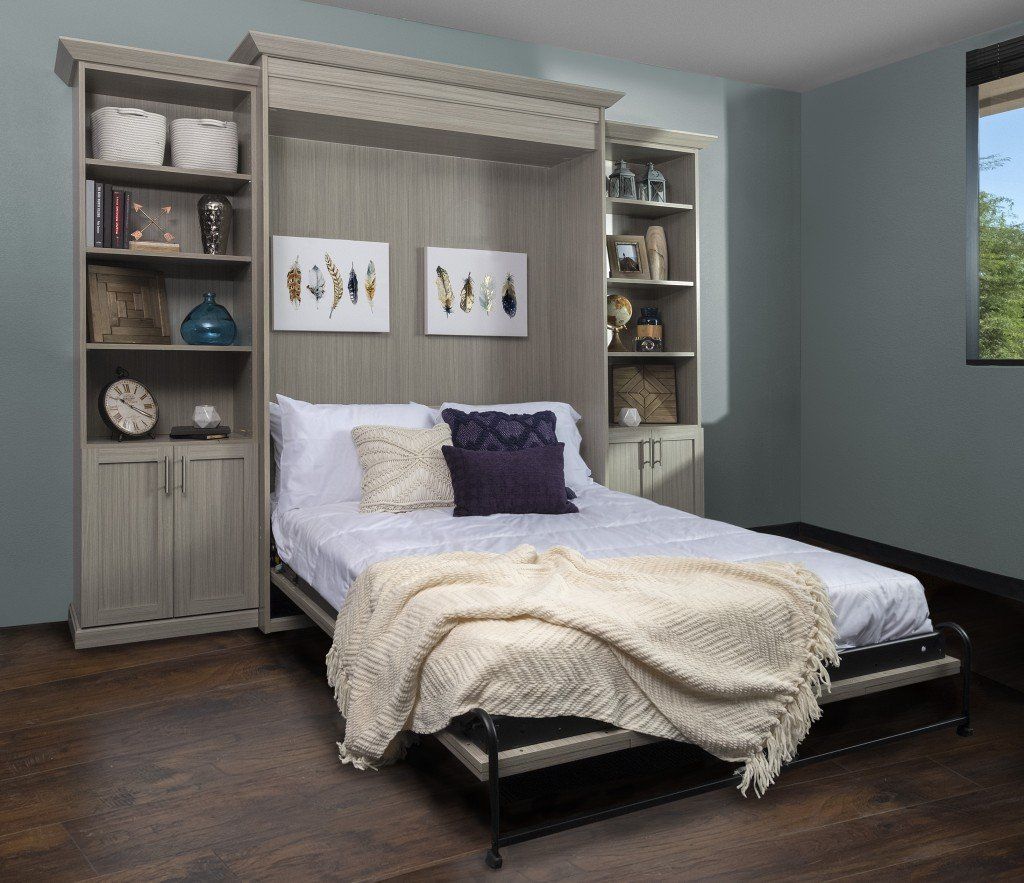 Cozy bedroom with a white bed, built-in shelves, gray walls, and dark wood flooring