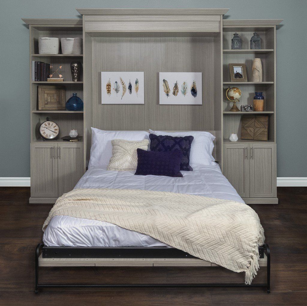 Modern bedroom with gray wood bed, shelves, white bedding, and purple accent pillows against a blue wall