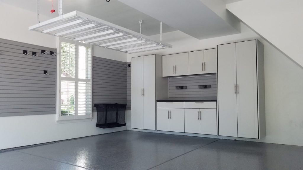 Bright garage with white cabinets, window, and overhead storage racks under a sloped ceiling