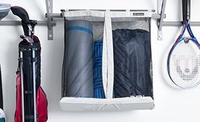 Hanging fabric organizer with folded bags and gear, beside a golf club bag and tennis racket