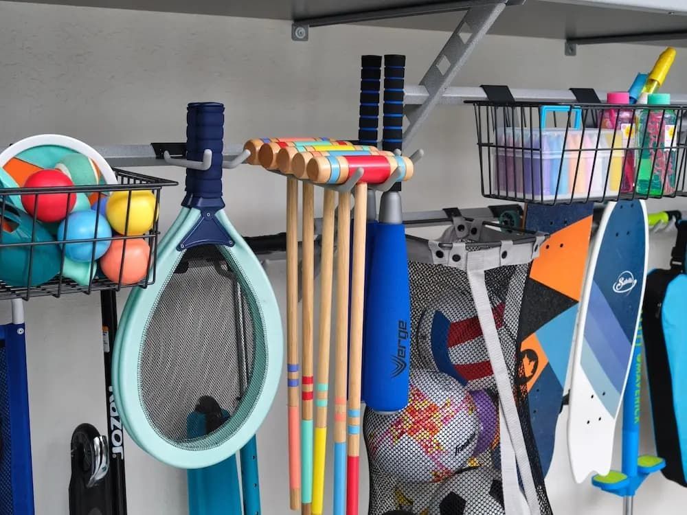 Colorful tennis rackets, balls, and sports gear organized on a shelf.