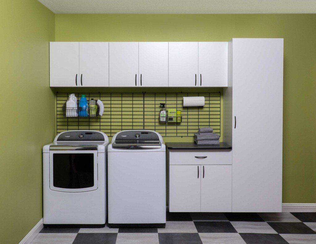Modern laundry room with white washer, dryer, cabinets, green backsplash, and black-and-white floor tiles