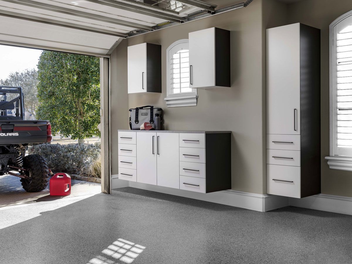 Garage interior with white and dark gray storage cabinets along the wall and an open garage door.