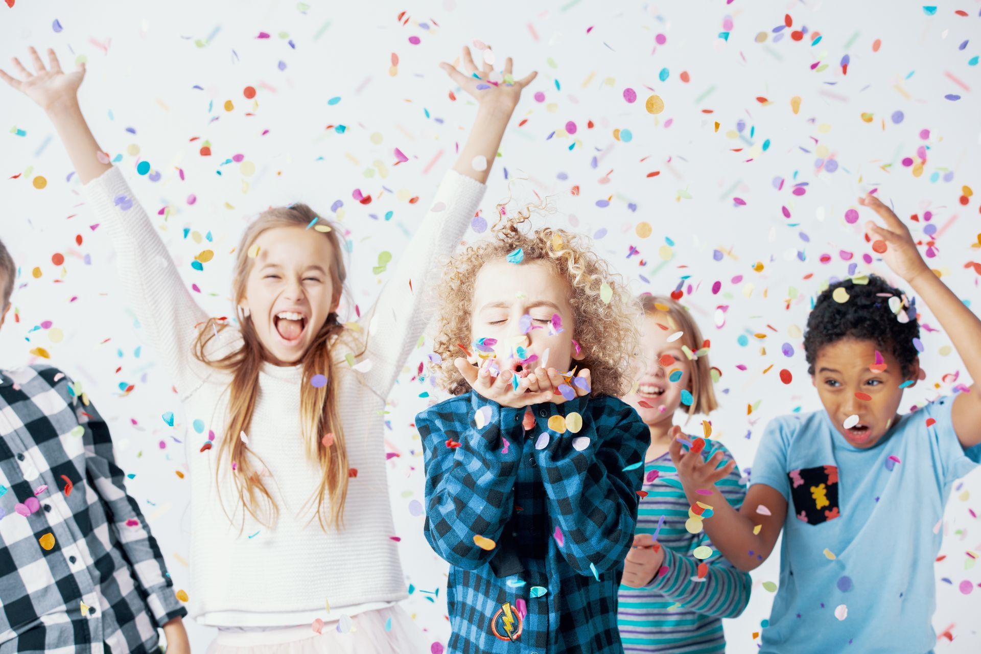 Children tossing colorful confetti into the air against a bright white backdrop.