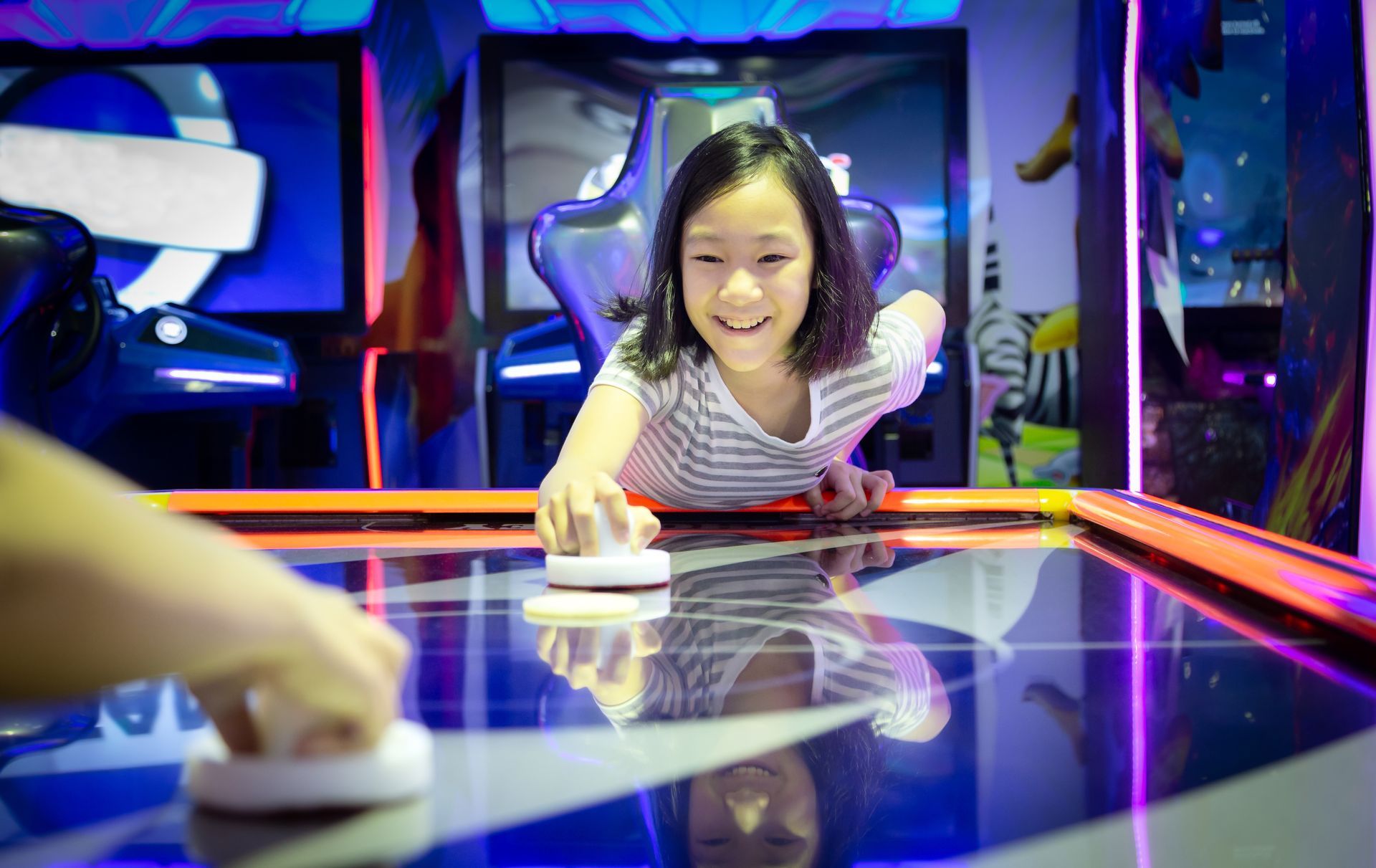 Little girl playing the arcade game of slide hockey with another child. Little girl playing the arcade game of slide hockey with another child.