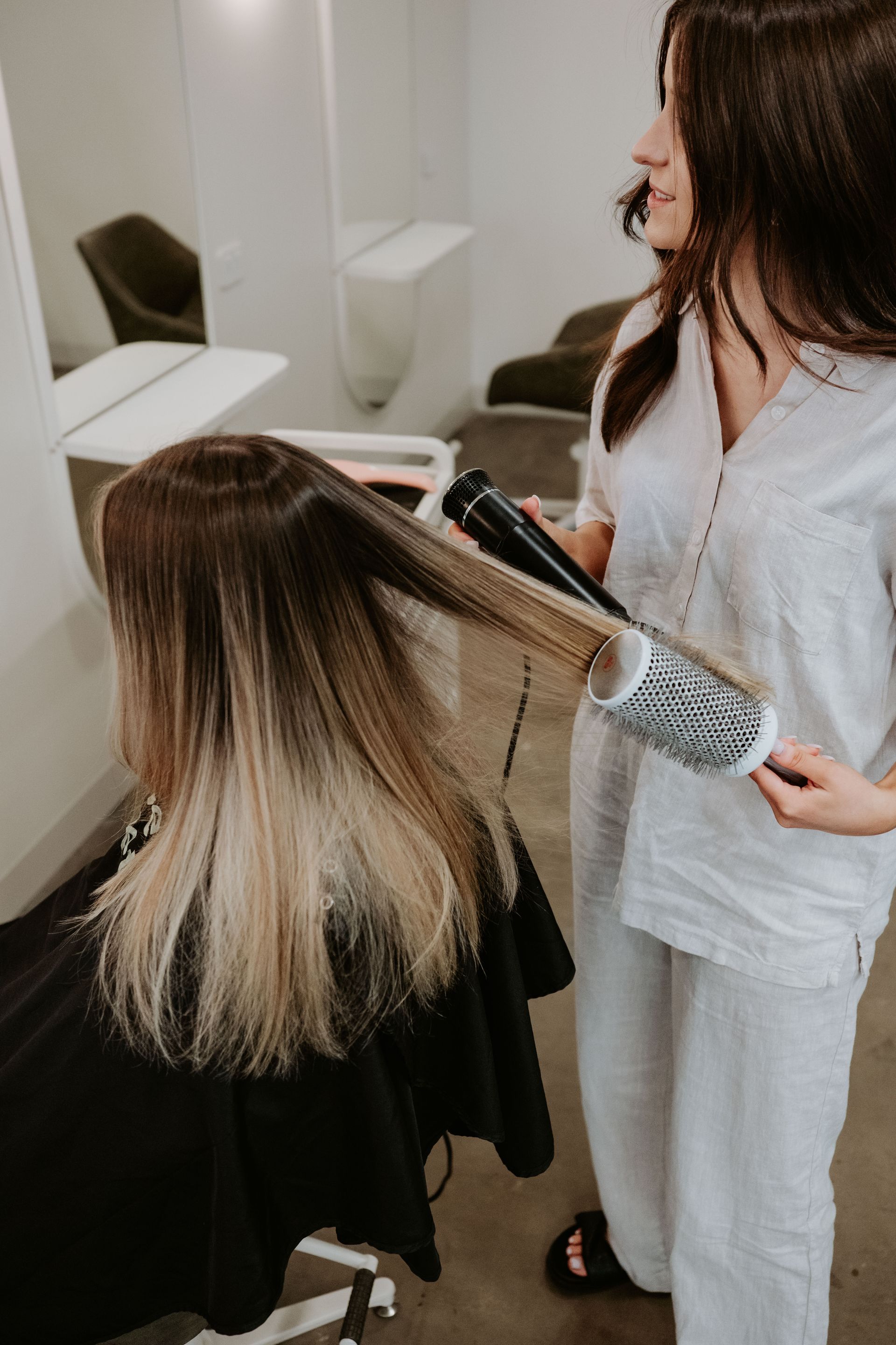 A Woman Is Getting Her Hair Done By A Hairdresser In A Salon — Rowe Street Collective In Shepparton, VIC