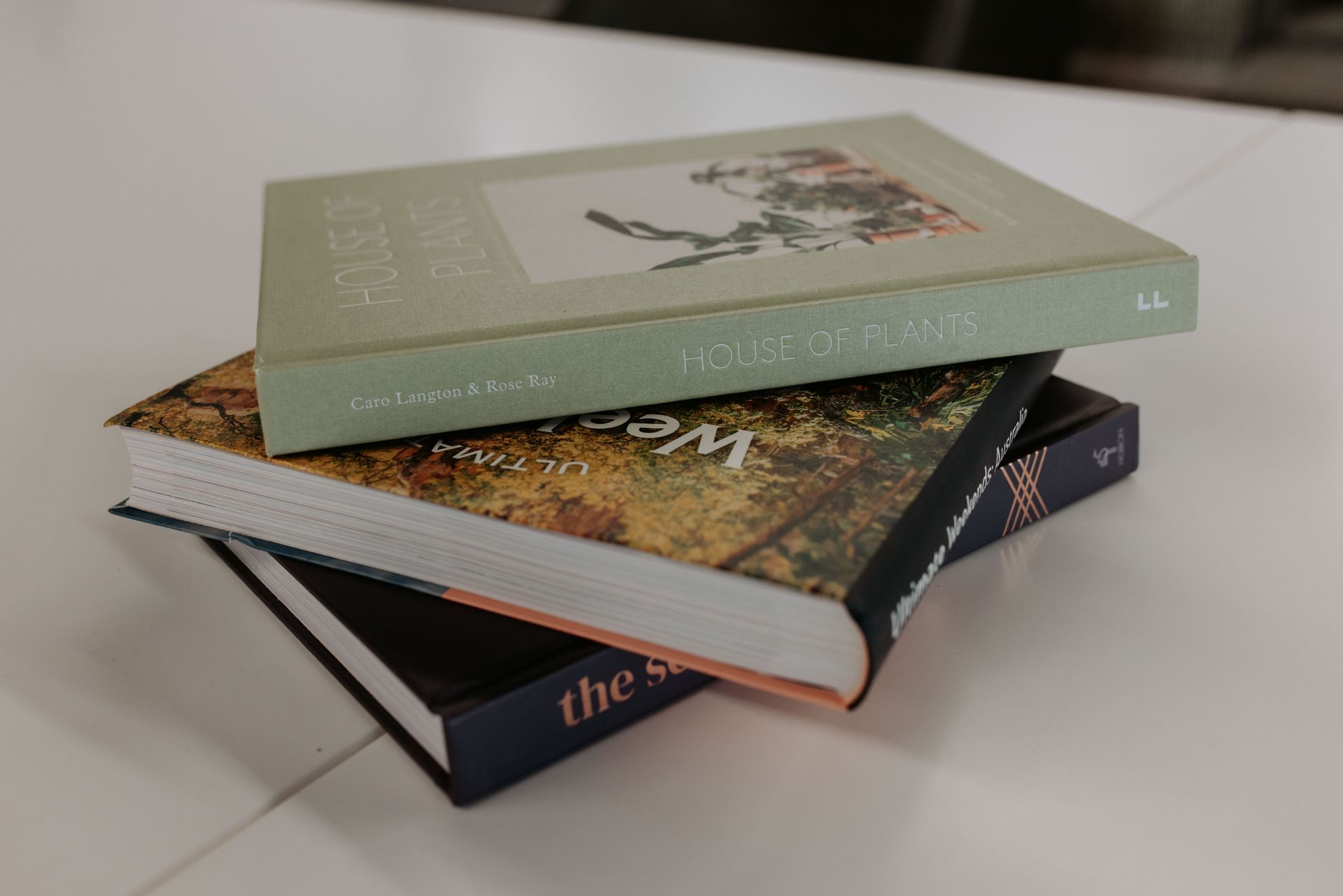 Three books are stacked on top of each other on a table. — Rowe Street Collective In Shepparton, VIC