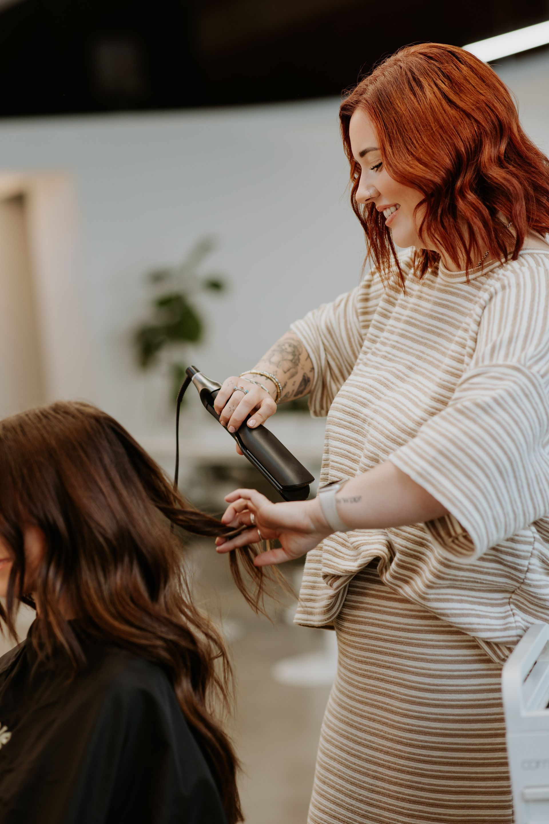 A woman is getting her hair straightened by a hairdresser in a salon. — Rowe Street Collective In Shepparton, VIC