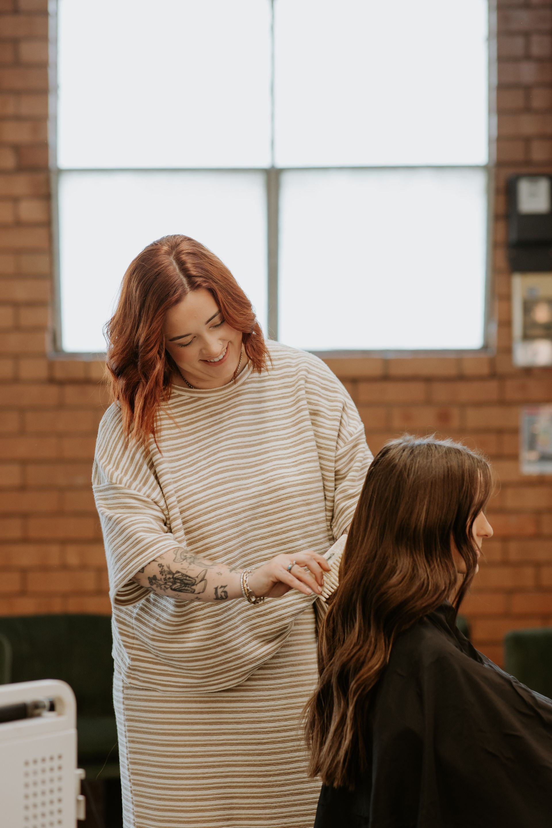 A woman is blow drying another woman 's hair in a salon. — Rowe Street Collective In Shepparton, VIC