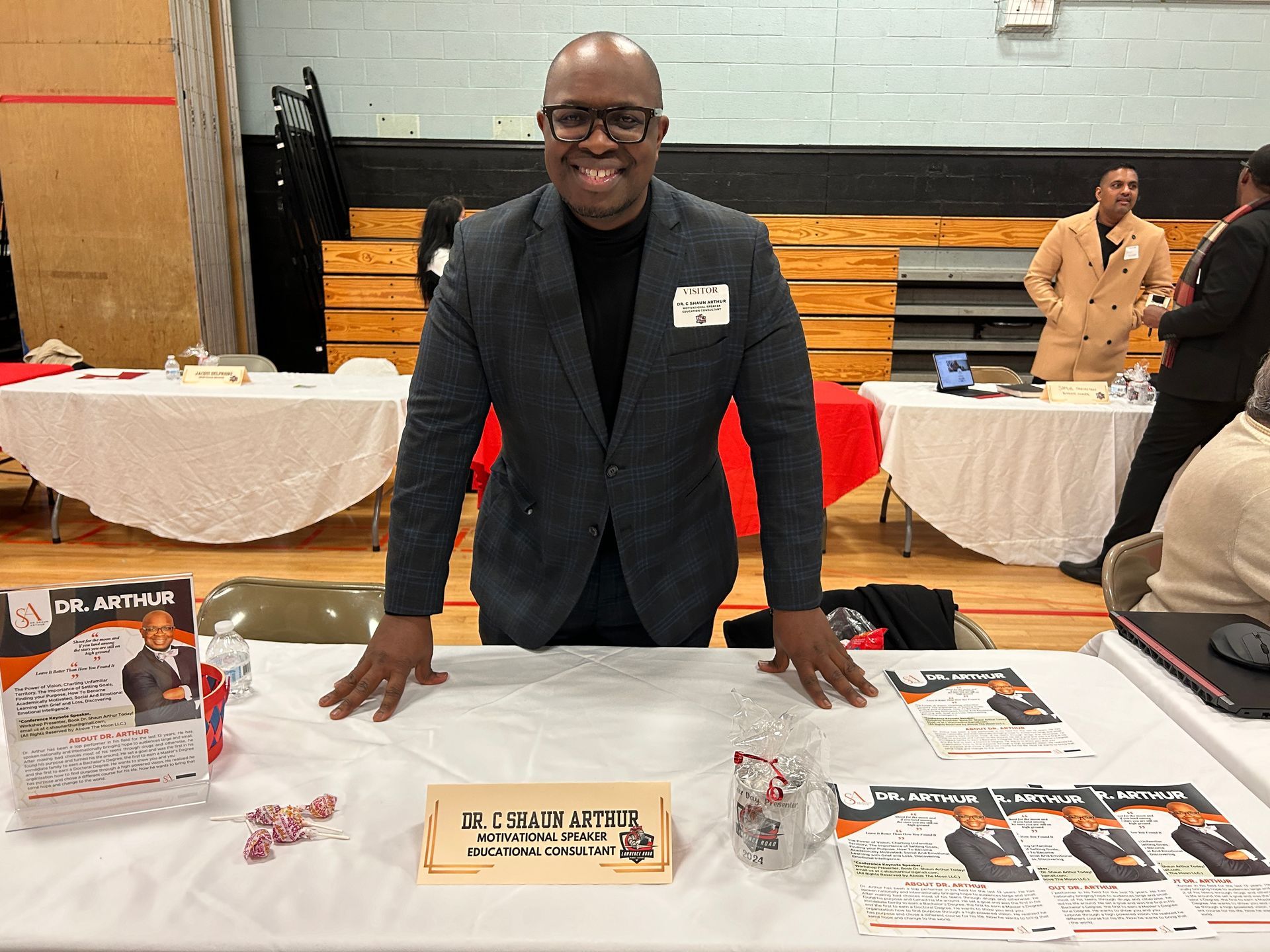 A man in a suit is standing at a table at a job fair.