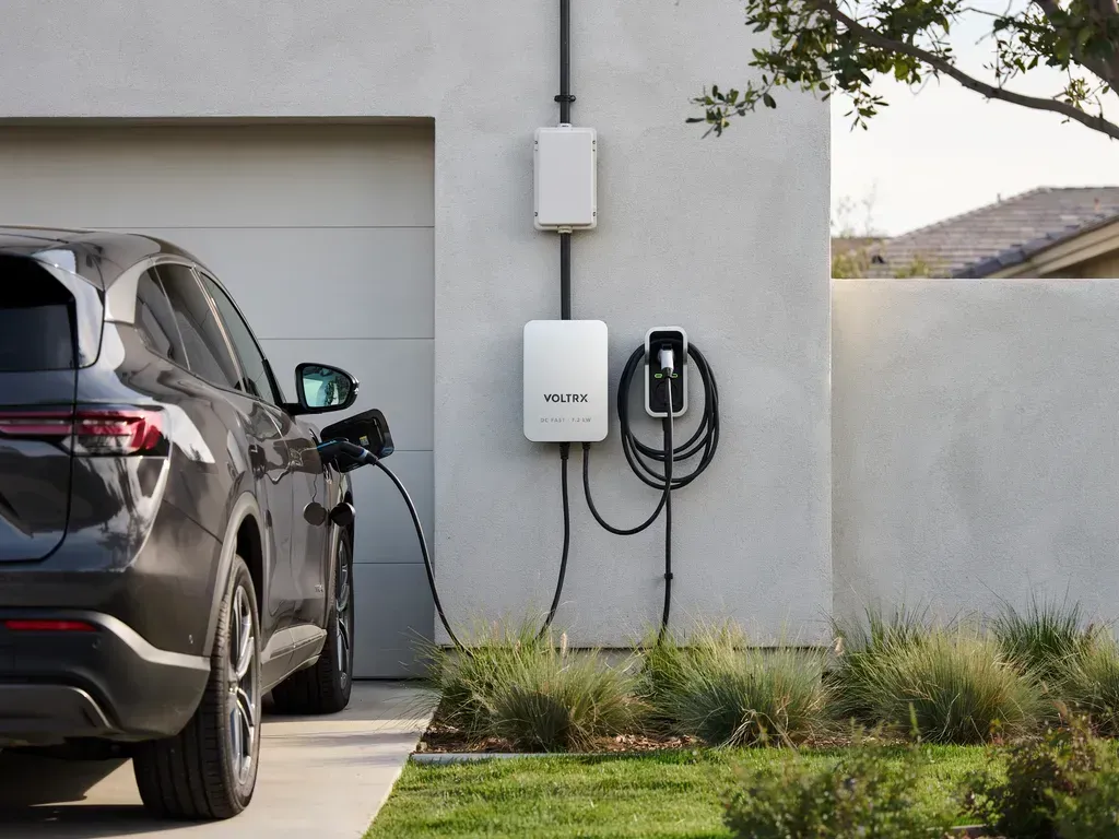 Electric SUV charging beside a wall-mounted home EV charger in a driveway