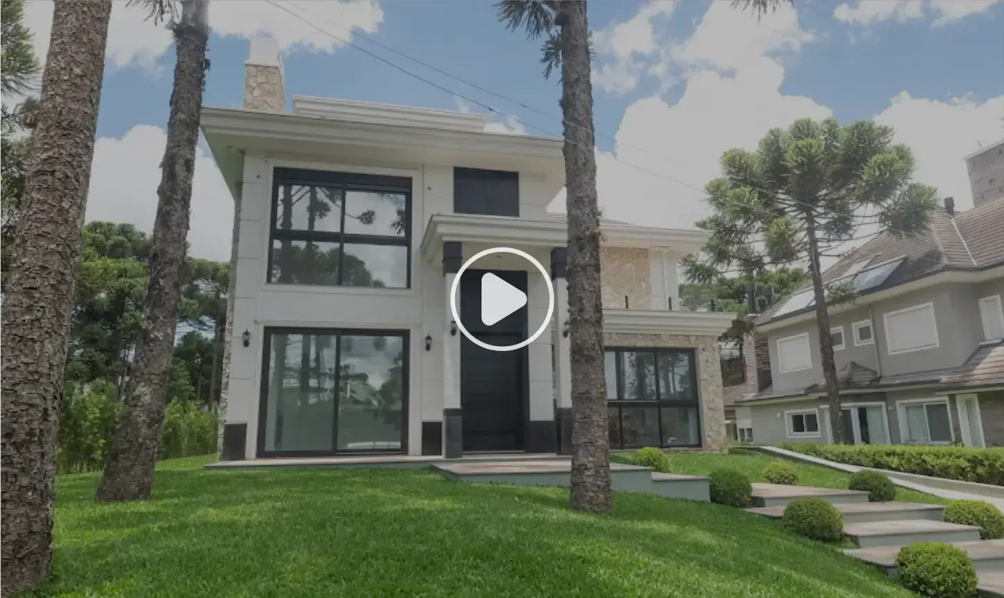 Casa moderna de dois andares com detalhes em preto e grandes janelas, cercada por árvores e gramado verde.