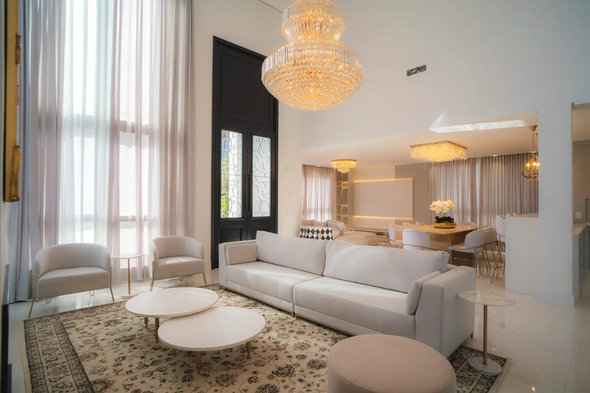 Sala de estar luxuosa com decoração branca, um grande lustre e um tapete persa.