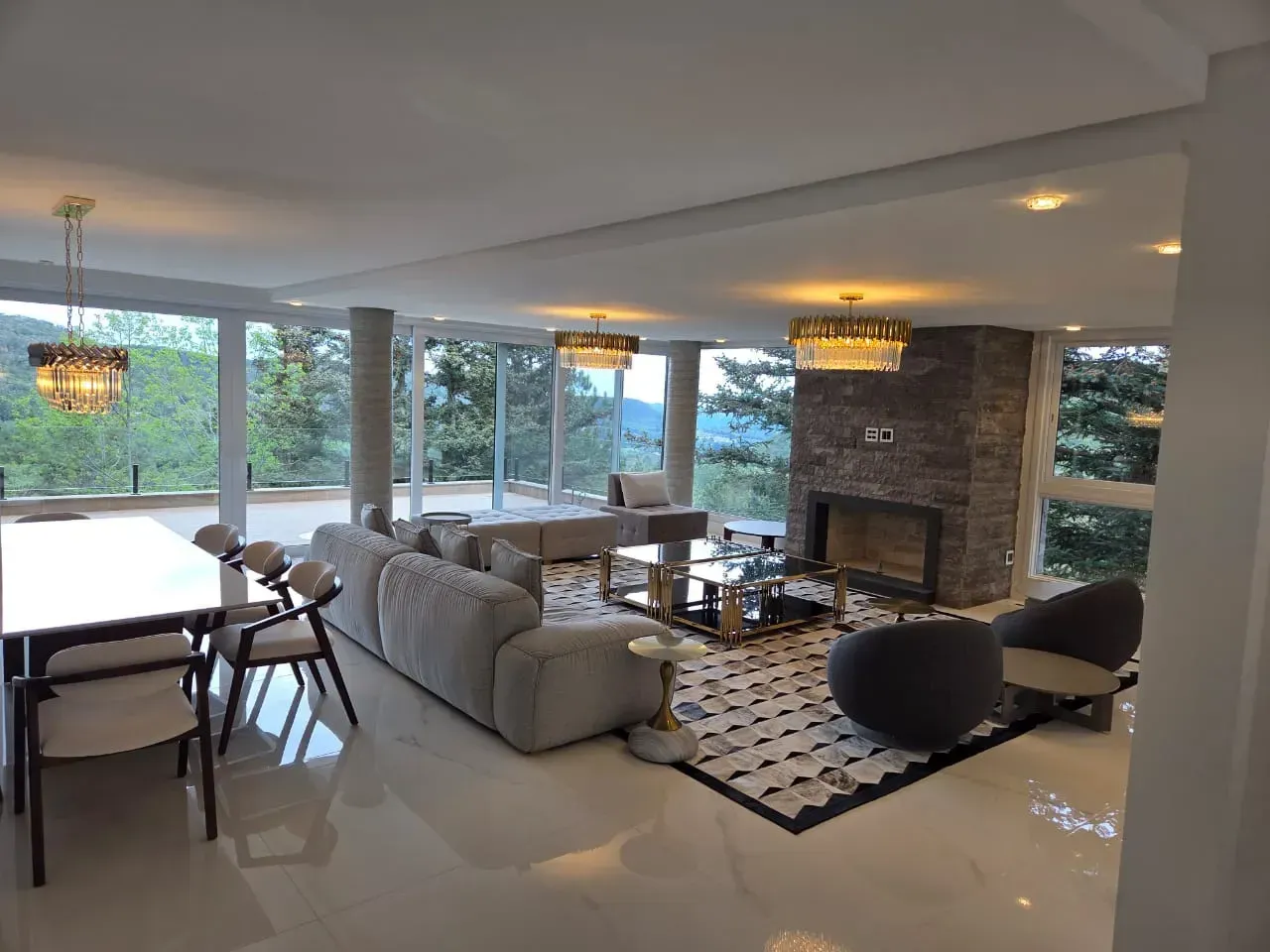 Sala de estar espaçosa com grandes janelas, lareira e mobiliário moderno; com vista panorâmica.