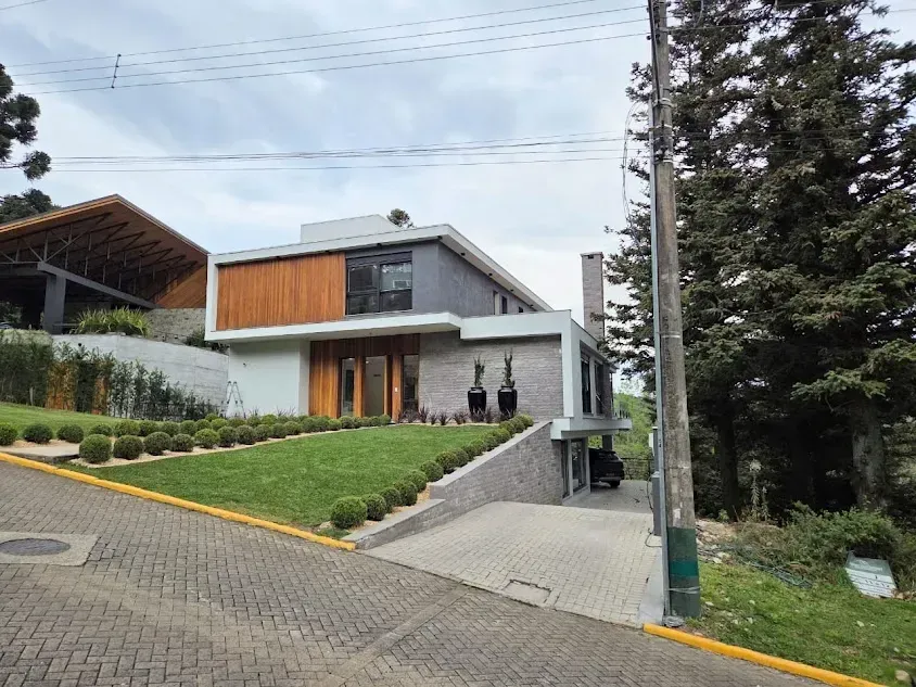 Casa moderna com detalhes em madeira e uma entrada de automóveis em declive num dia nublado.