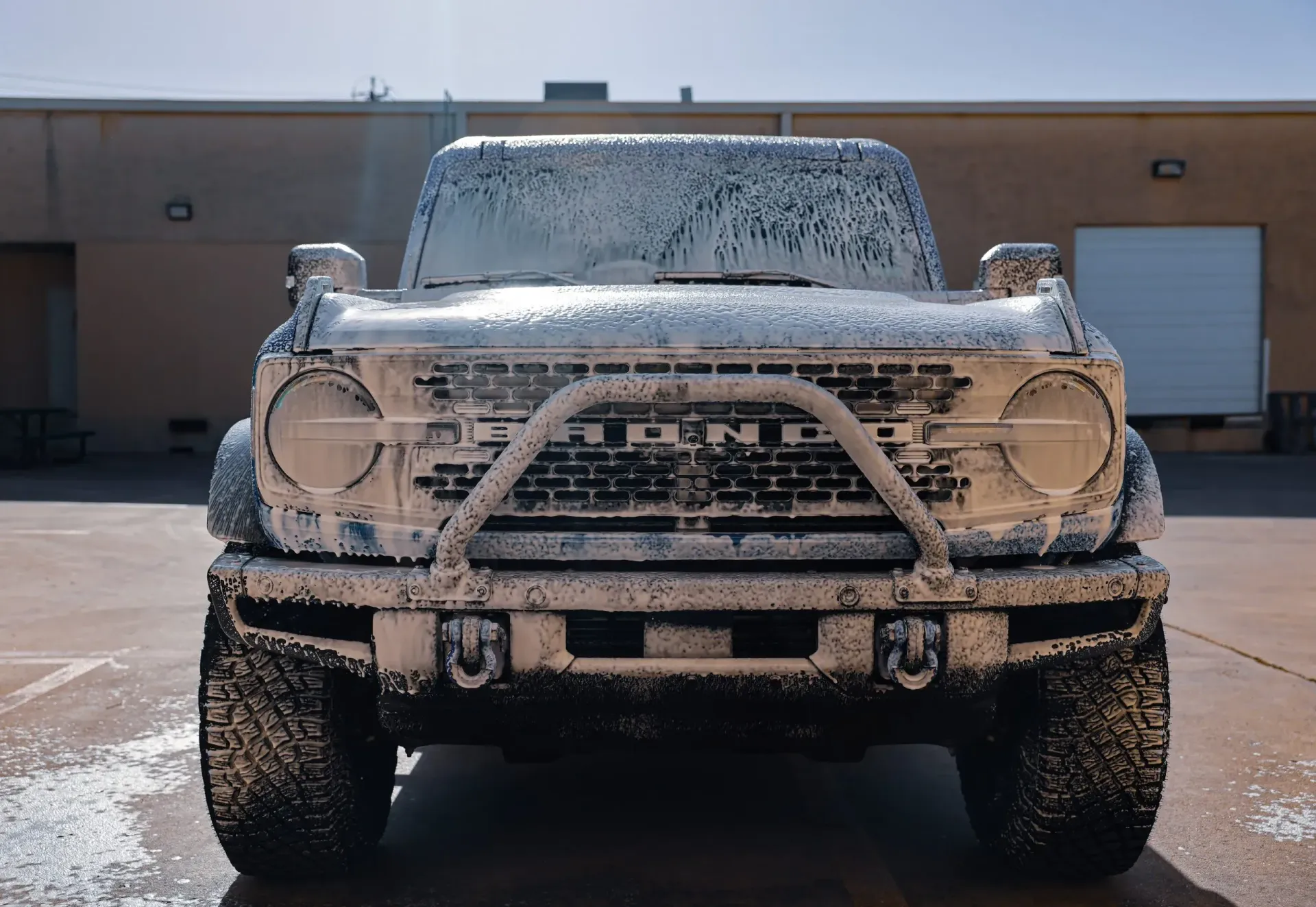Ford Bronco covered in white foam, ready for washing.