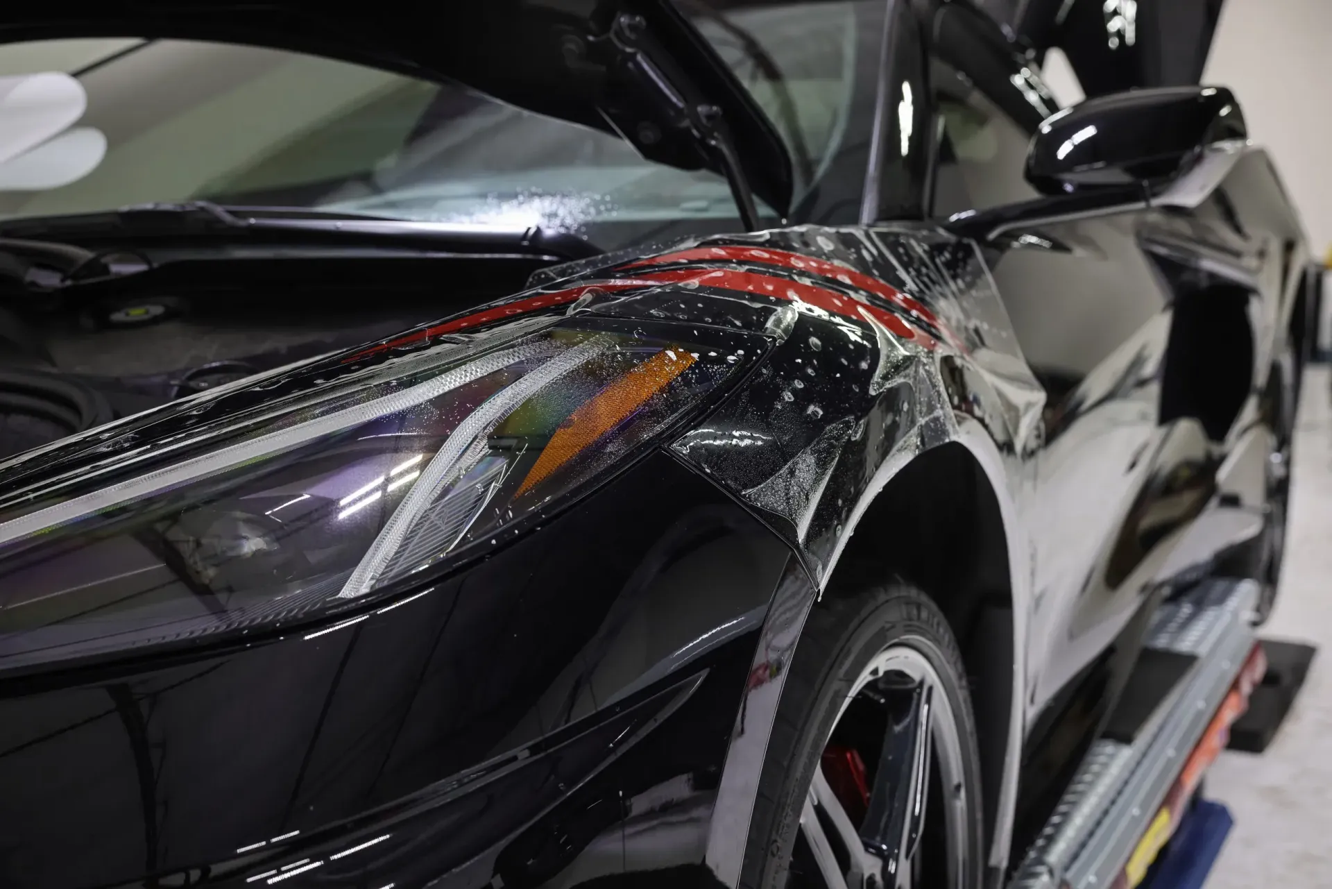 Black sports car with protective film applied to the front quarter panel.