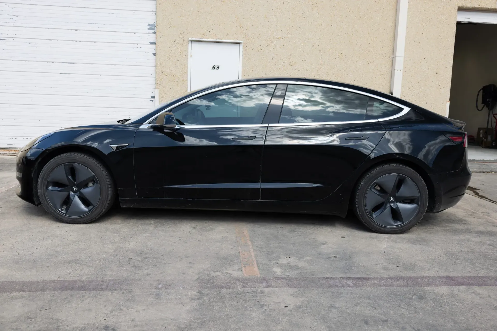 Black Dodge Charger covered in soapy foam, being washed outdoors.