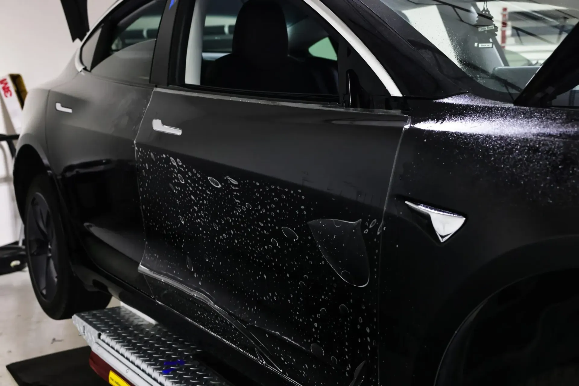 Black Tesla car door being wrapped, partially completed.