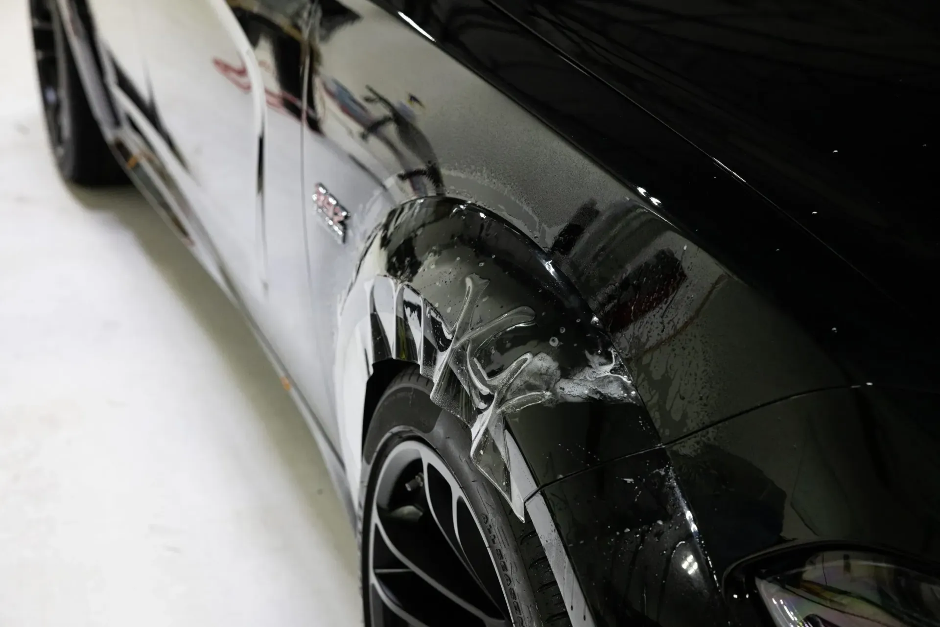 Damaged black car fender with visible paint peeling above tire.