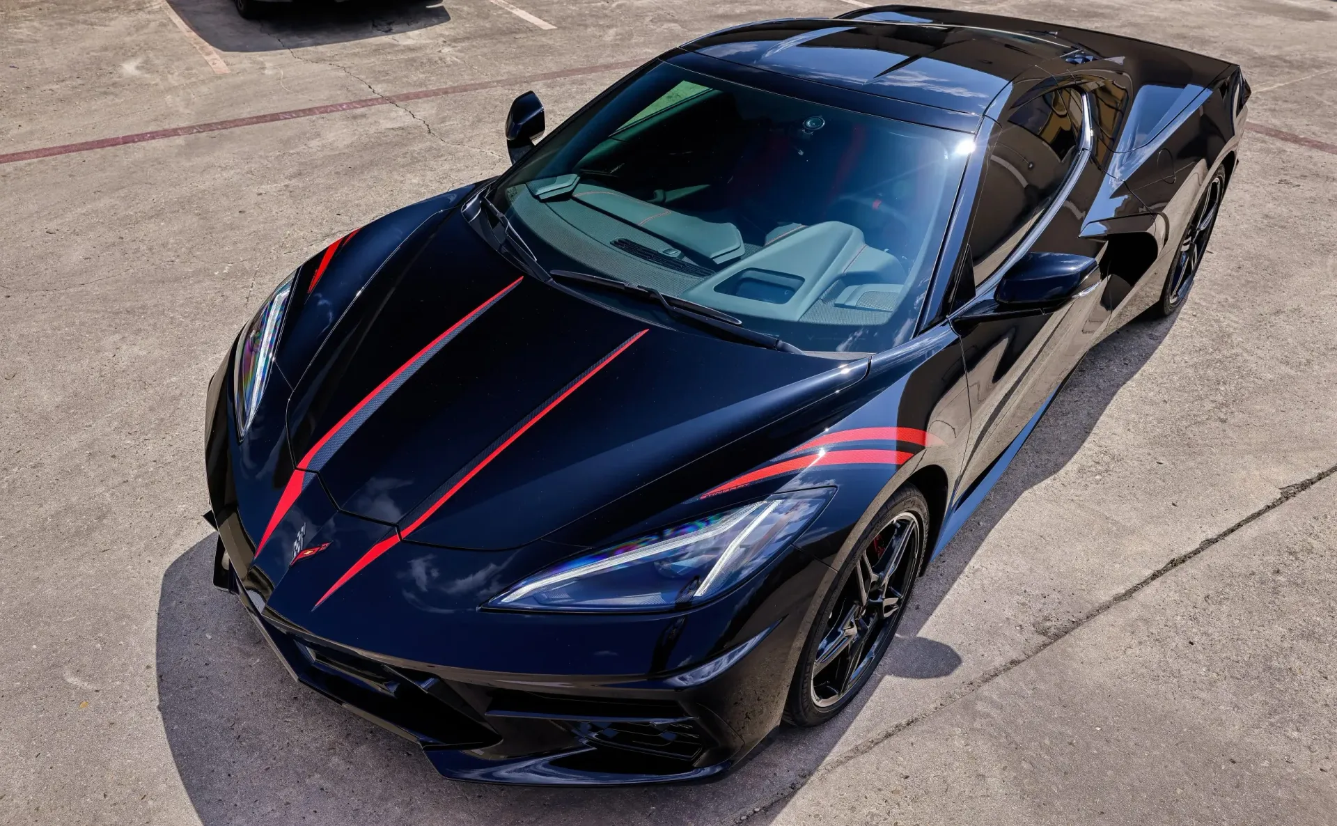 Black Corvette sports car with red stripes parked on concrete.