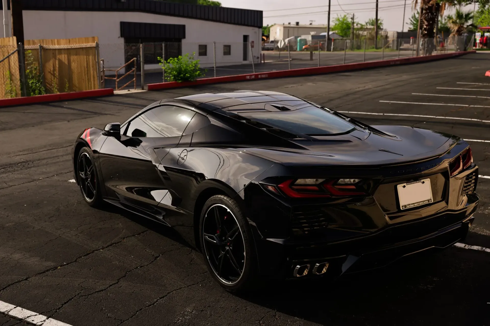 Black sports car parked in a parking lot, near a building.