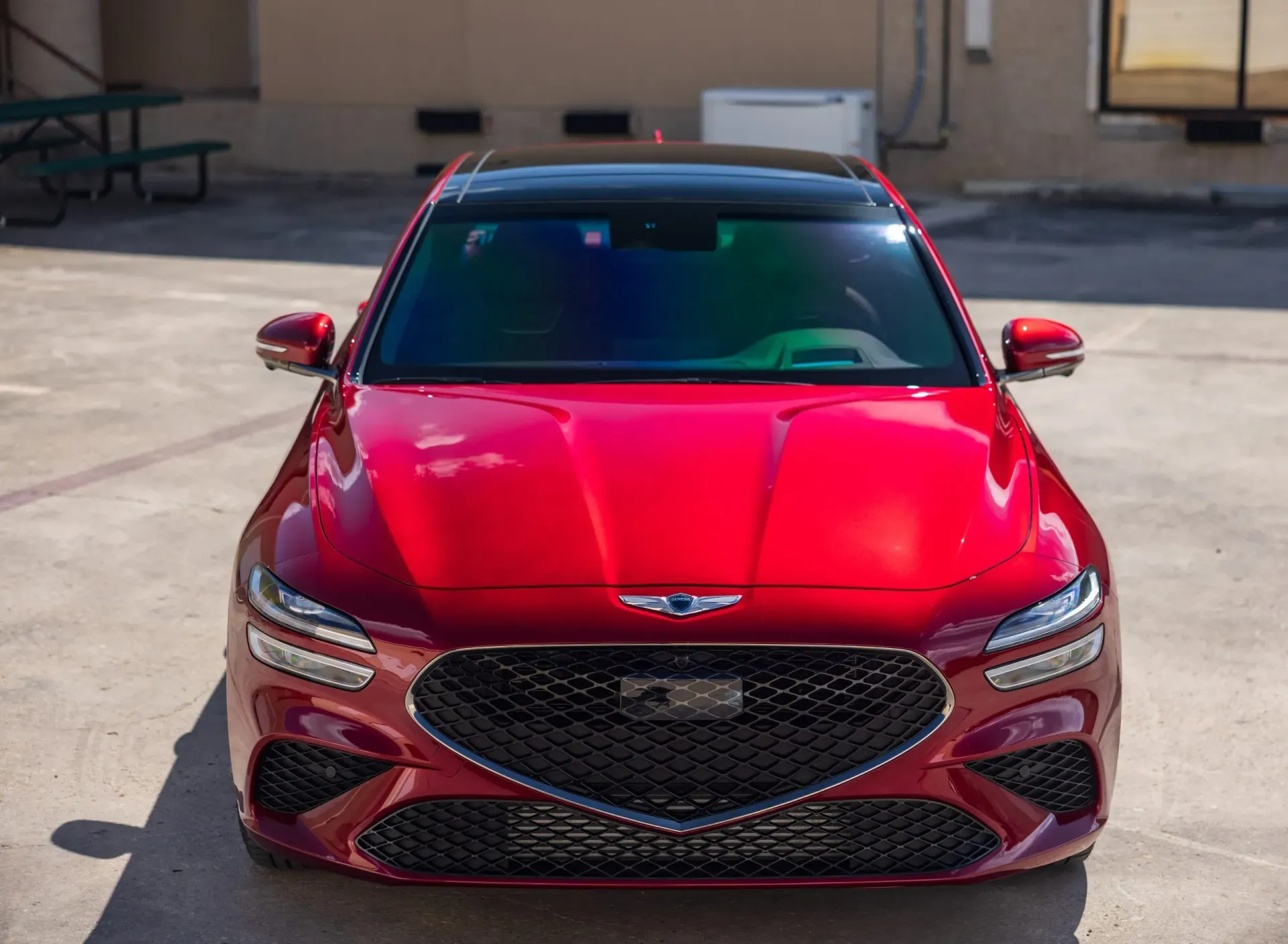 Red Genesis G70 sedan parked on concrete, with a black roof and a dark front grill.
