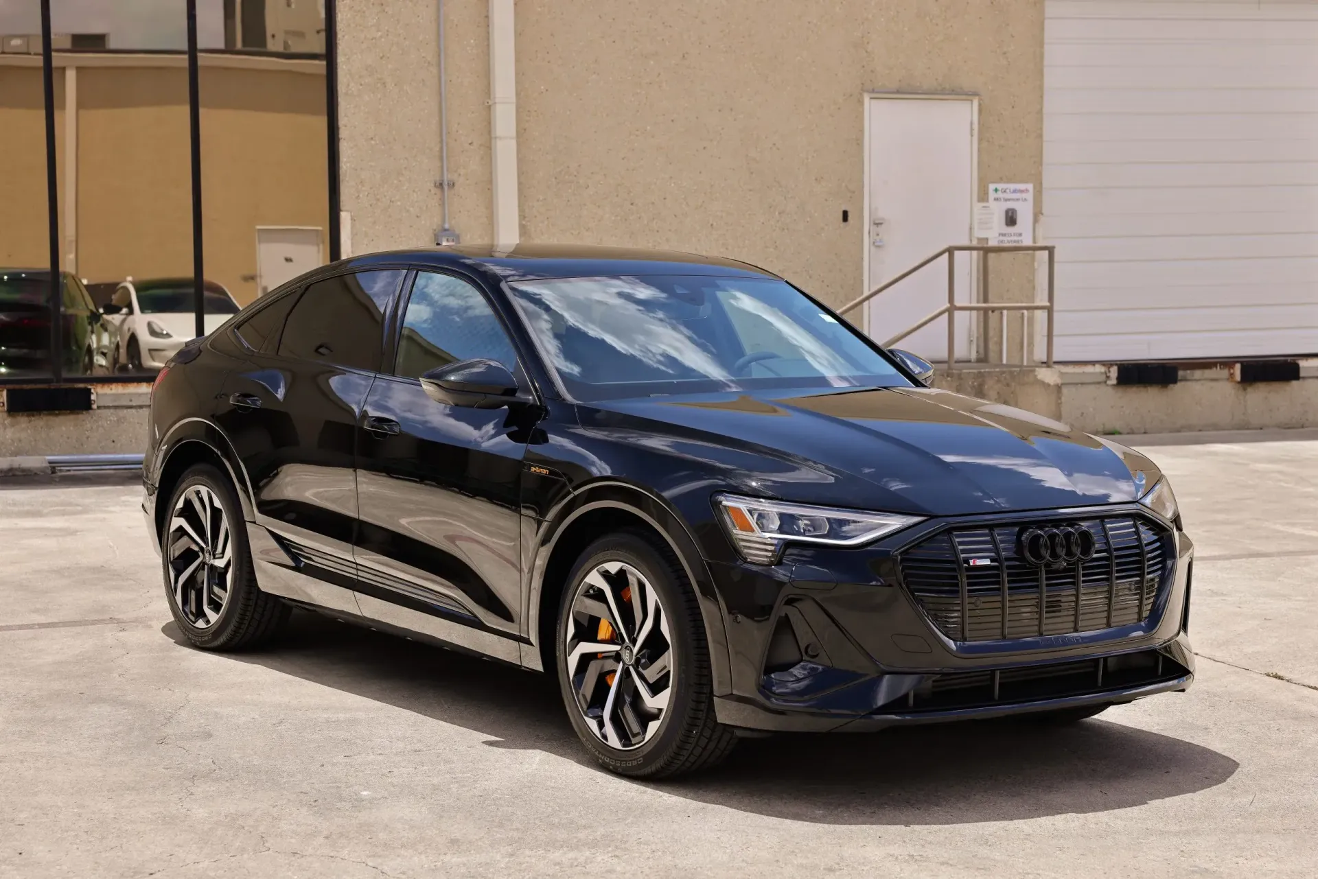 Black Audi e-tron SUV coupe parked outdoors. Metallic wheels, orange brake calipers.