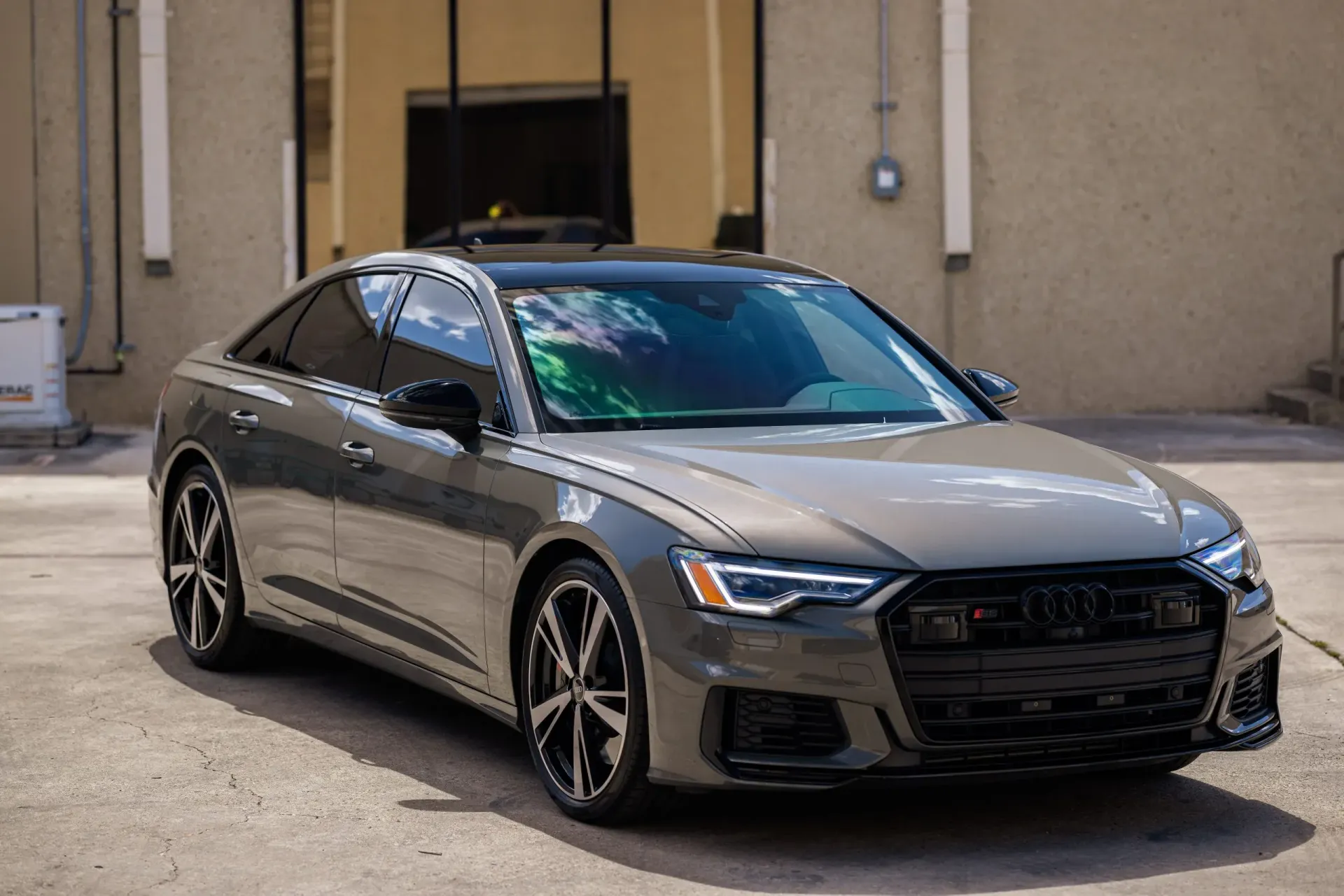 Gray Audi sedan parked in front of a building with black accents and a black roof.