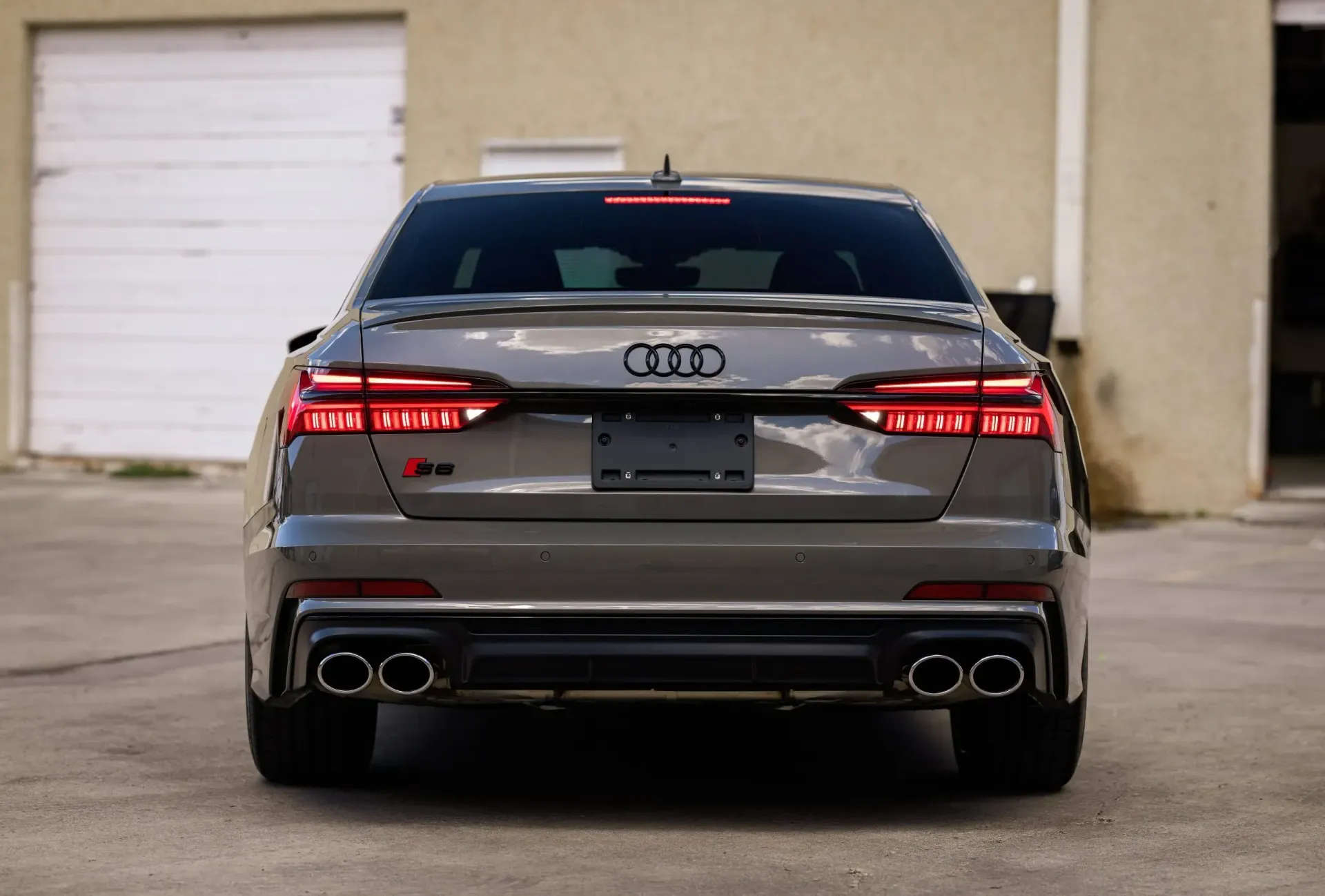 Gray Audi S5 sedan rear view with black accents and quad exhaust pipes.