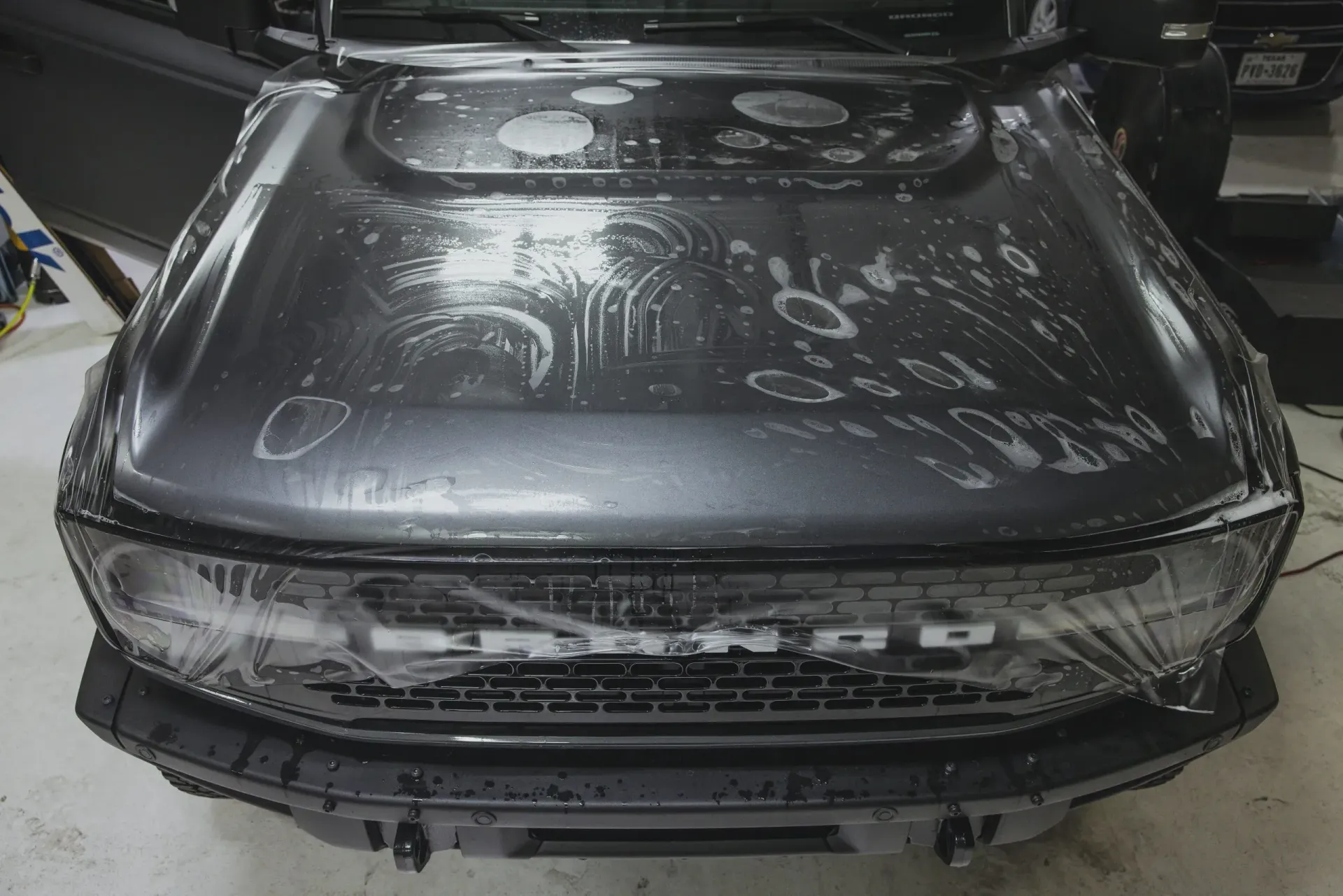 Grey truck hood covered in soapy water, being prepped for paint protection film.