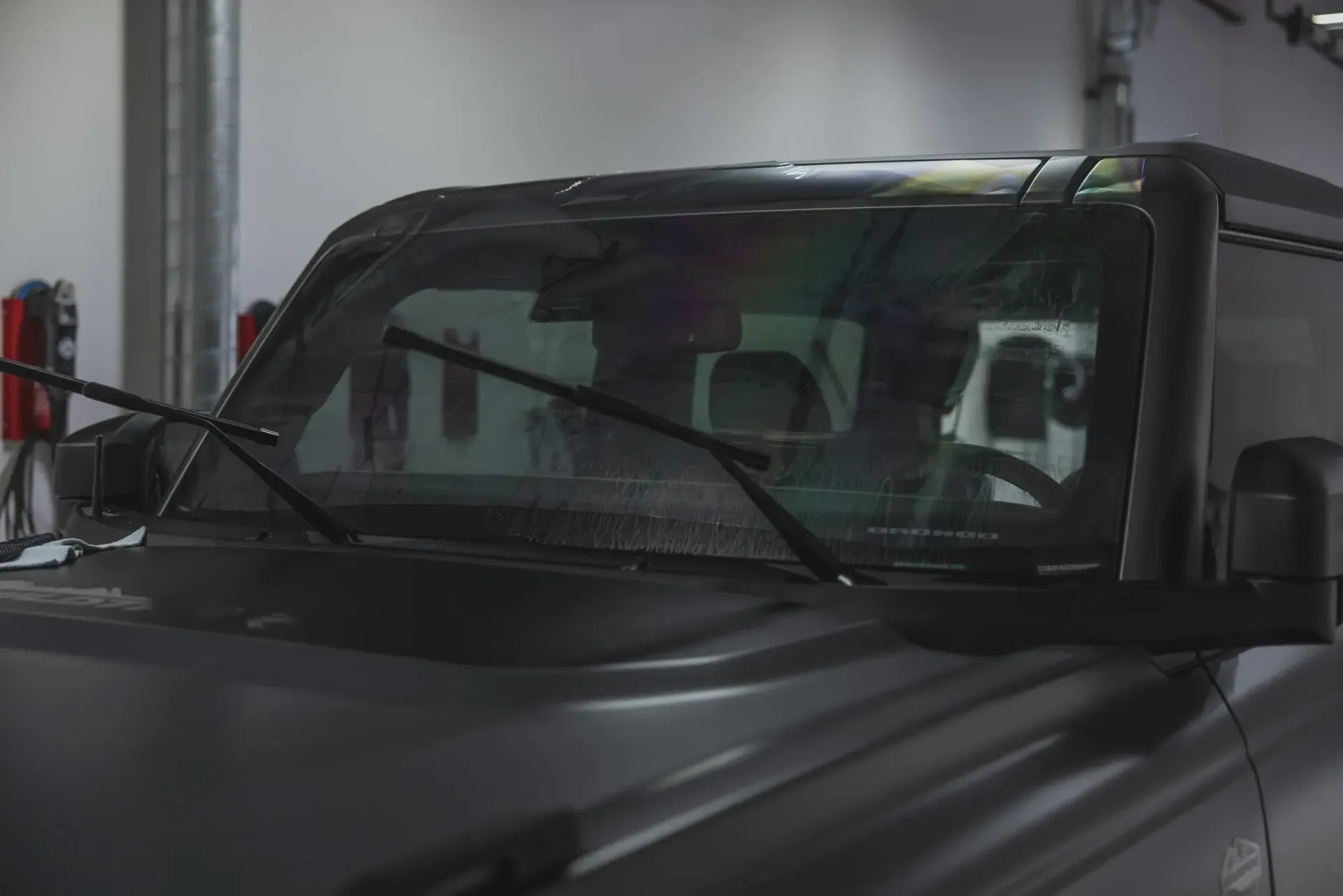Black SUV with windshield wipers on in a garage.