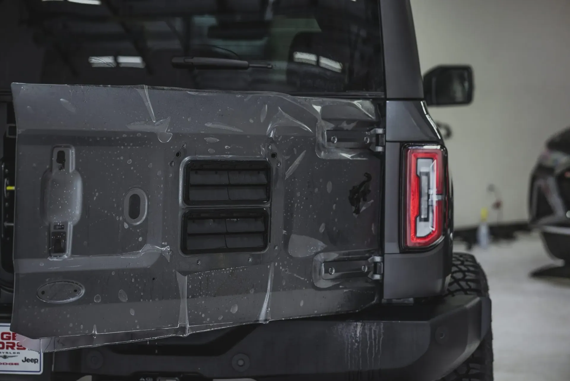 Gray SUV rear door with clear film applied, inside a garage.
