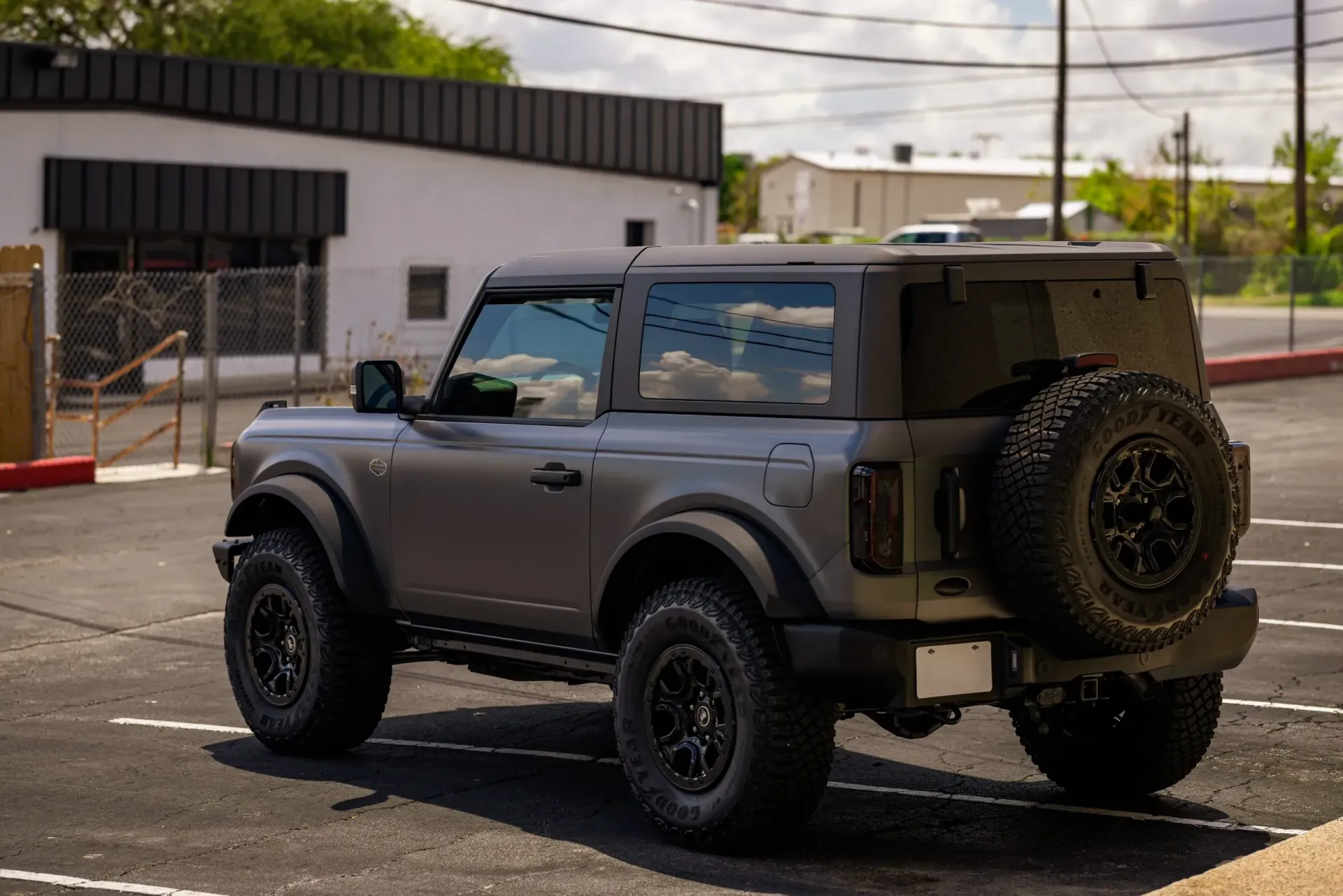 Gray Ford Bronco SUV parked in an outdoor lot, with black wheels and a spare tire.