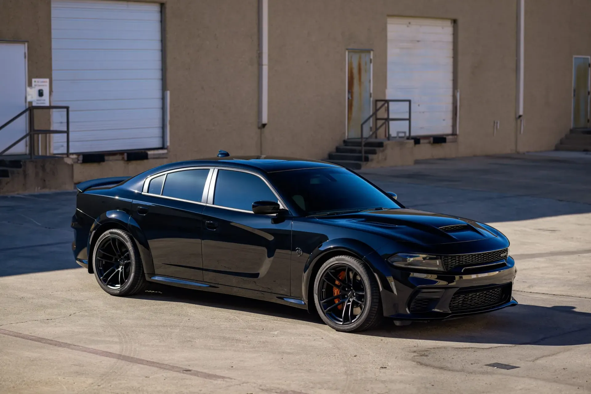 Black Dodge Charger parked in front of a building; daytime.