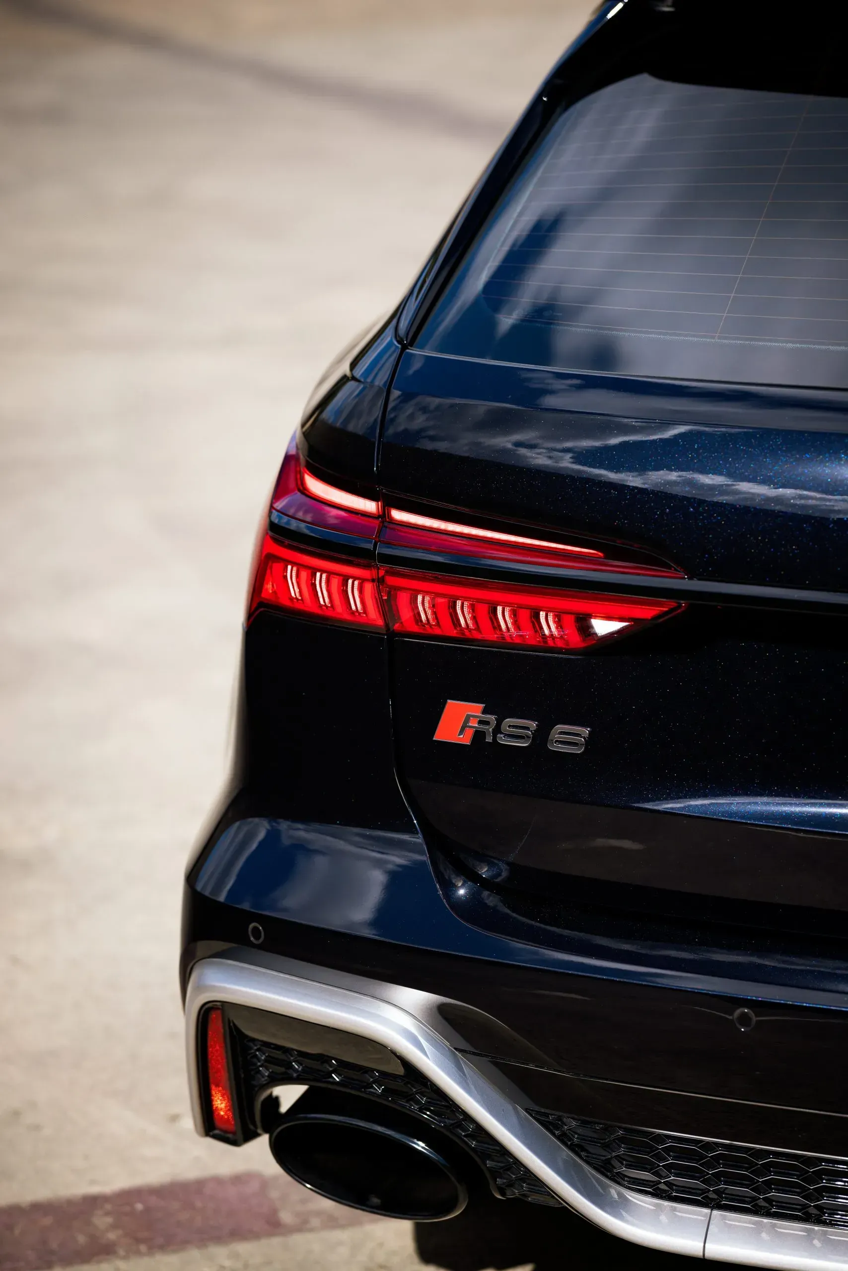 Black Audi RS 6 Avant's rear, showing taillights, exhaust, and RS 6 badge on a light background.