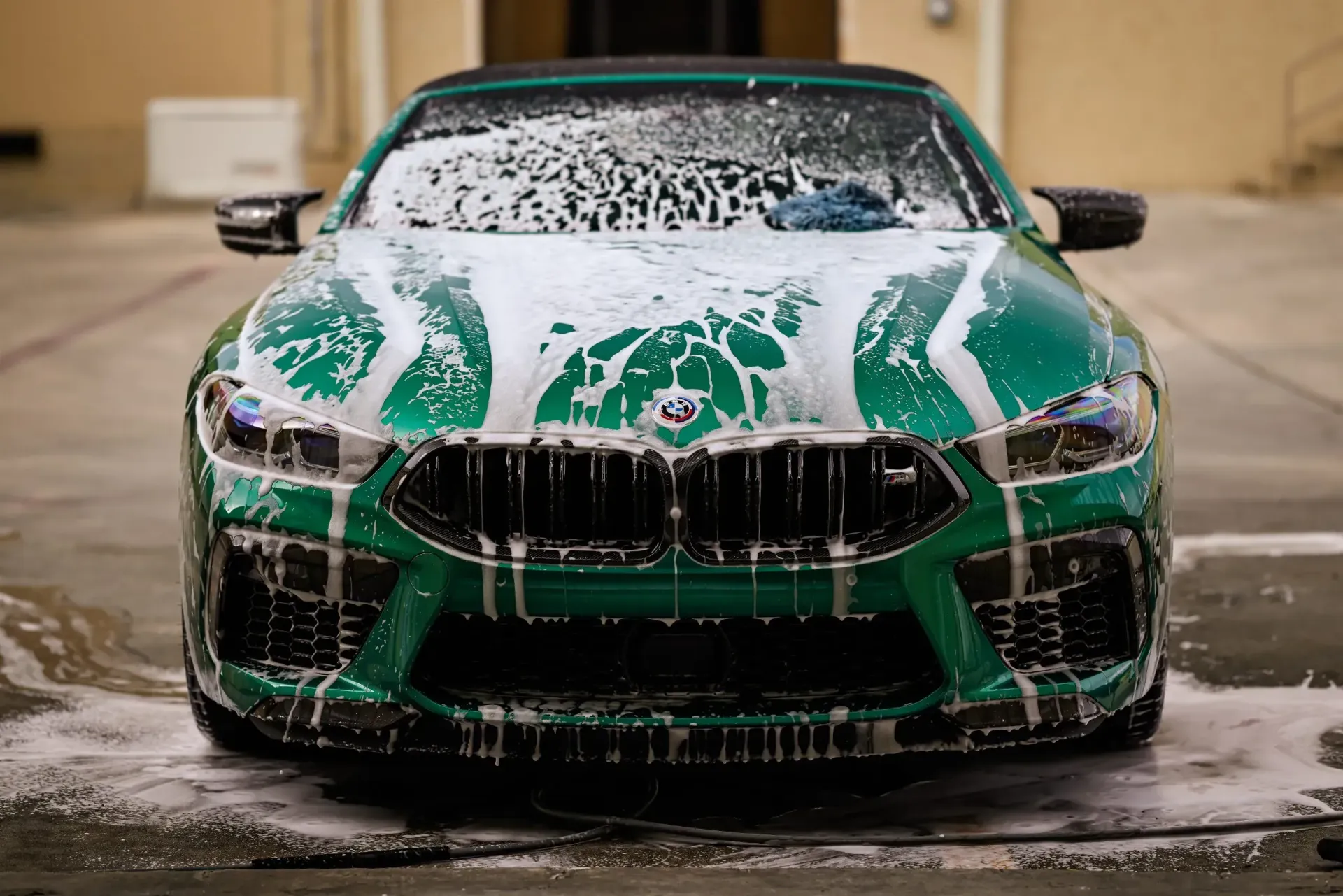 Green BMW covered in soapy foam, preparing for a wash.