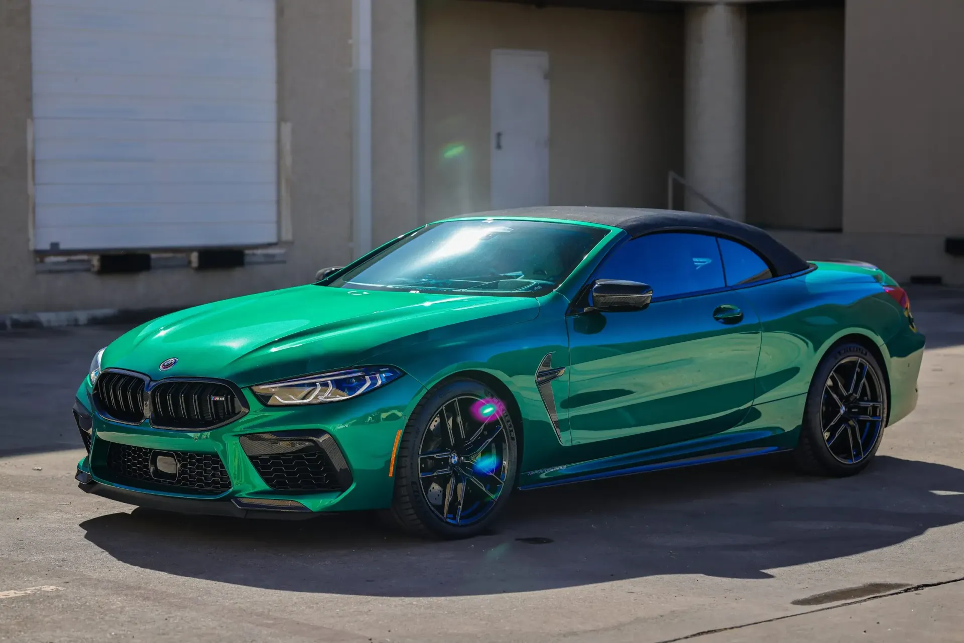 Green convertible BMW M8 parked outside a building.
