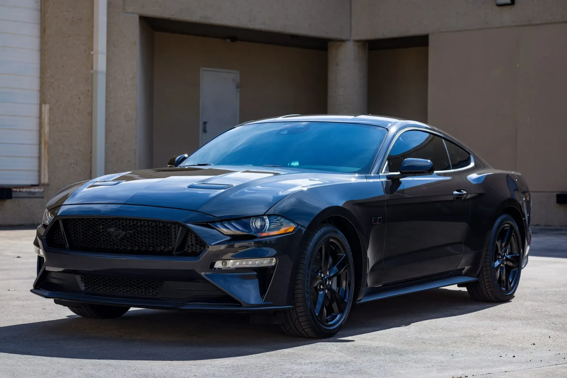 Black Ford Mustang parked in front of a building.