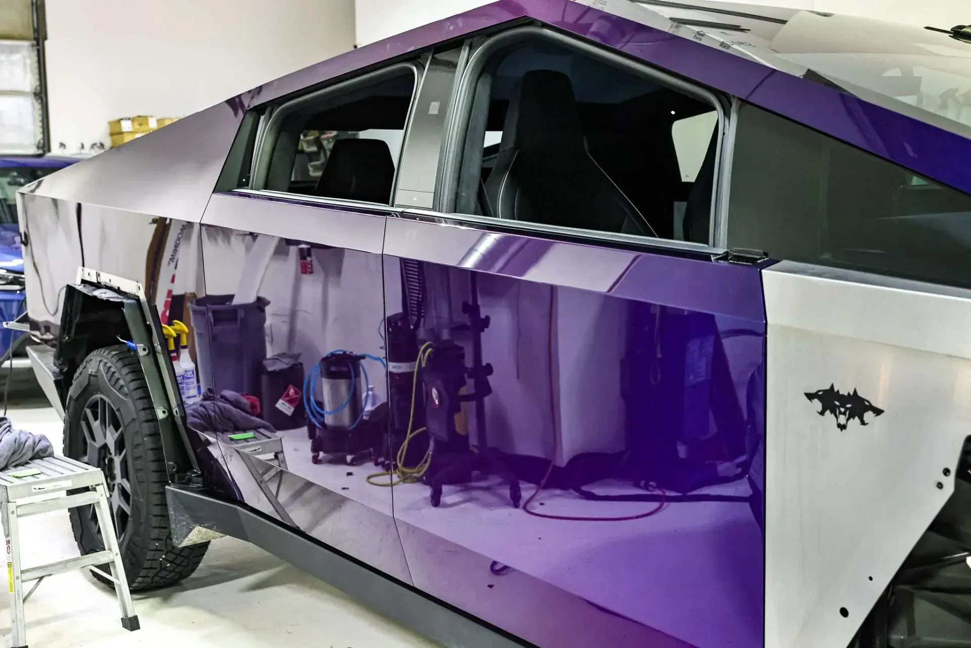 A purple wrapped Tesla Cybertruck being washed, inside a garage.