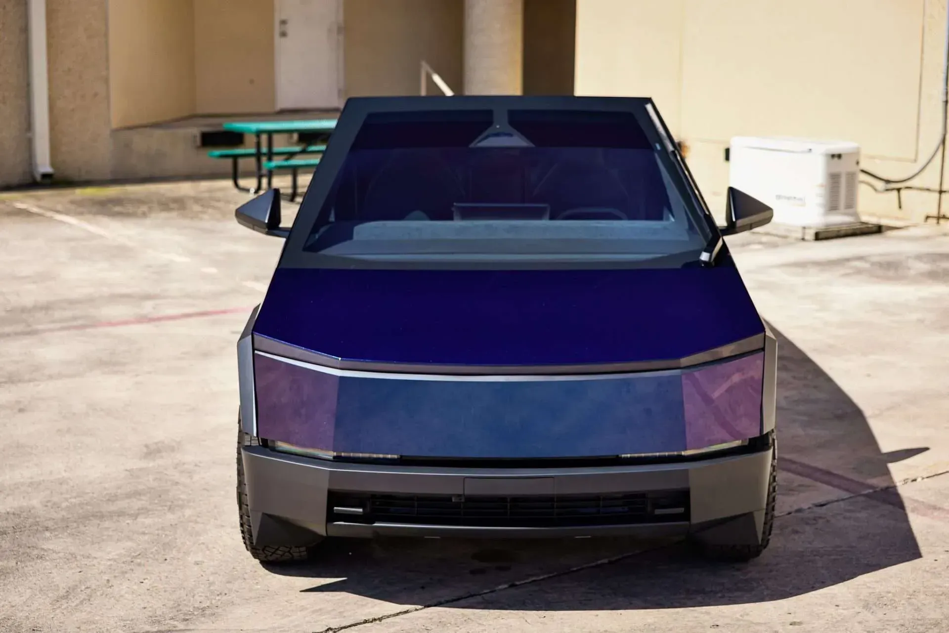 Front view of a dark blue, futuristic-looking pickup truck parked outside.