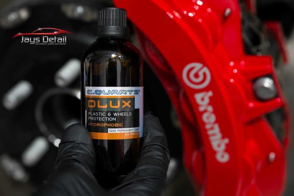 Person holding a bottle of car detailing product, in front of a red Brembo brake caliper.