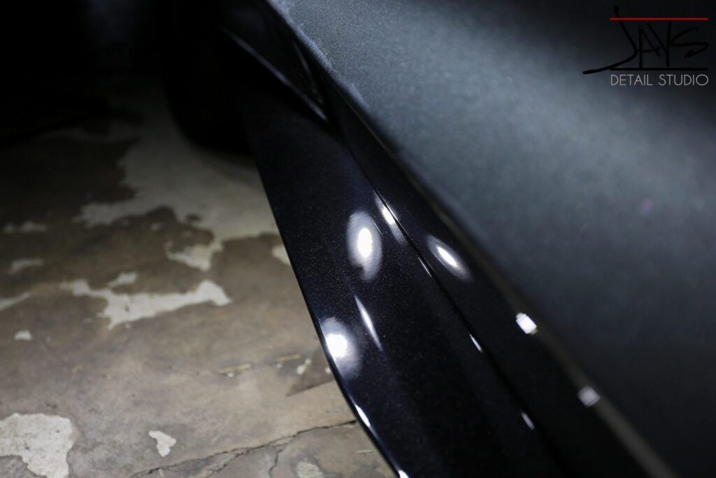 Black car door with reflections; detailing.