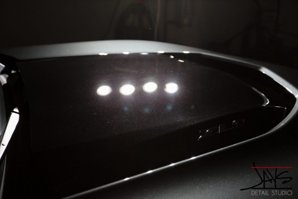 Red car door reflecting bright light against a black background.