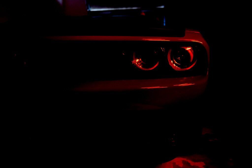 Red taillights of a Dodge Challenger in a dark setting, glowing brightly.