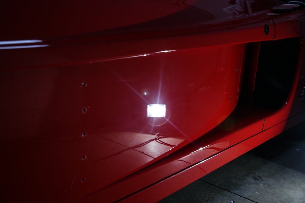 Red car side with shiny surface and white square light.