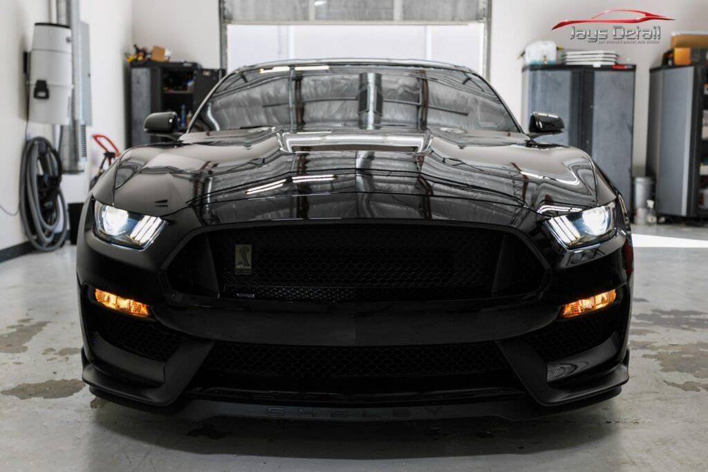 Black Ford Mustang, front view, in a garage.